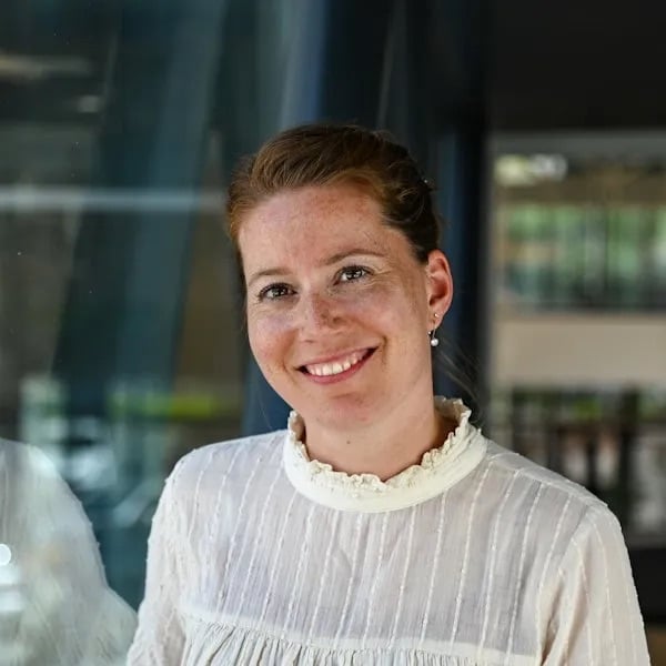 Vrouw kijkt lachend de camera in.