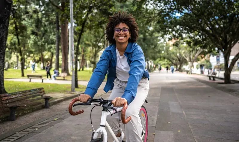 Vrouw met kroeshaar op een fiets lachend naar in de camera