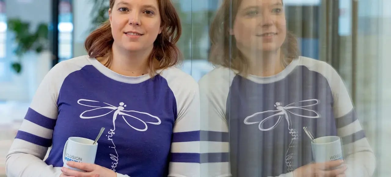 Woman holding a coffee cup, leaning against the window.