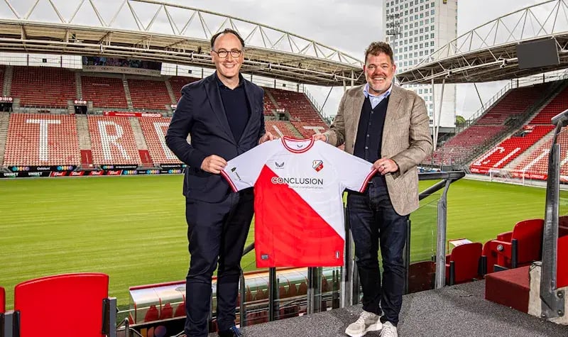 Two men holding an FC Utrecht shirt with the Conclusion sponsor name on it.