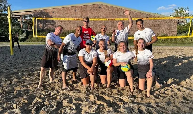 Group photo of colleagues on a volleyball court.