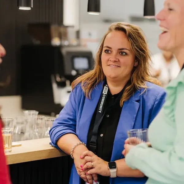 A woman in a blue blazer talks with others during an informal gathering.