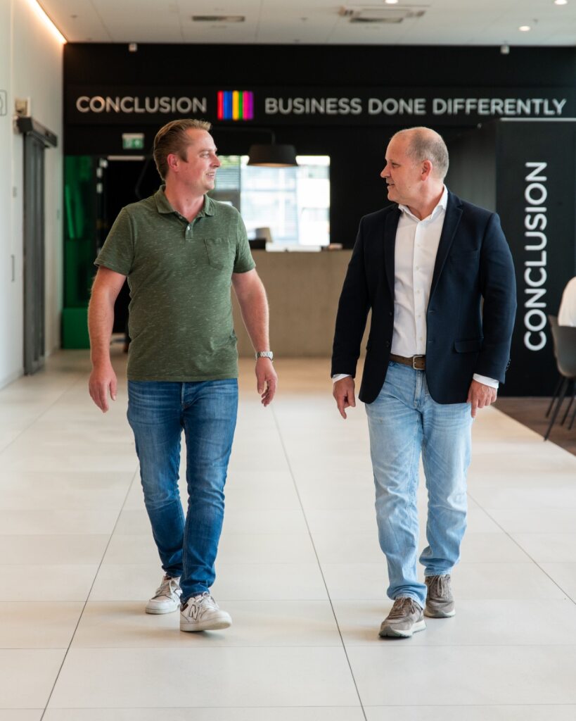 Twee mannen lopen door de lobby van Conclusion.