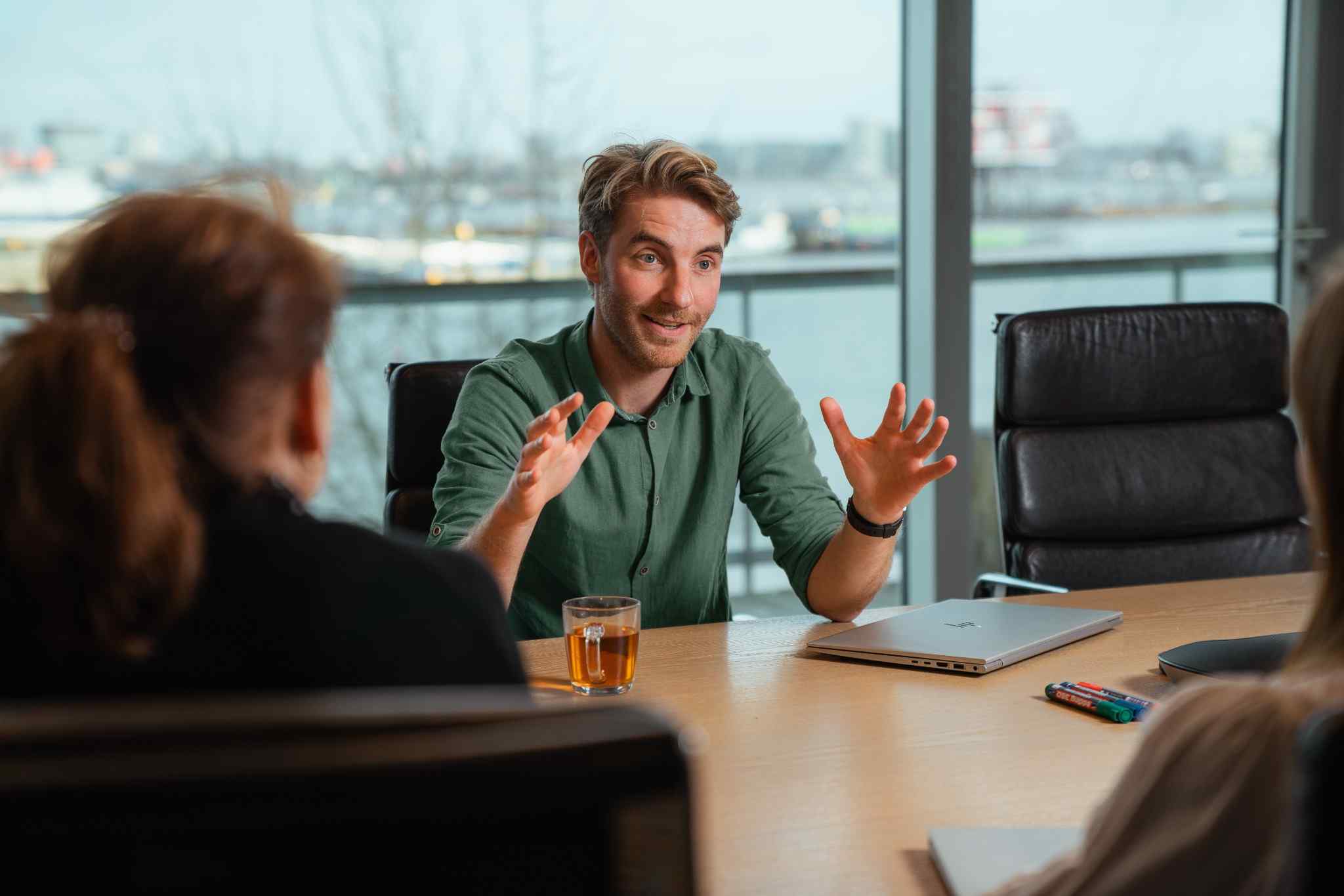 Man in green shirt explaining something in a meeting room.
