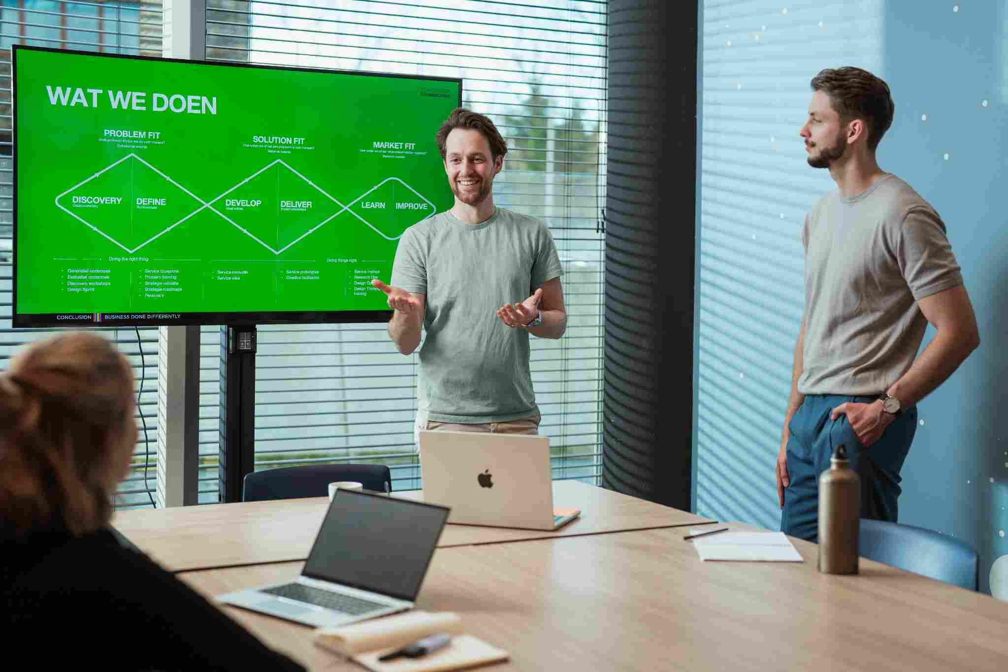 Man presenting in front of a green screen in a meeting room.