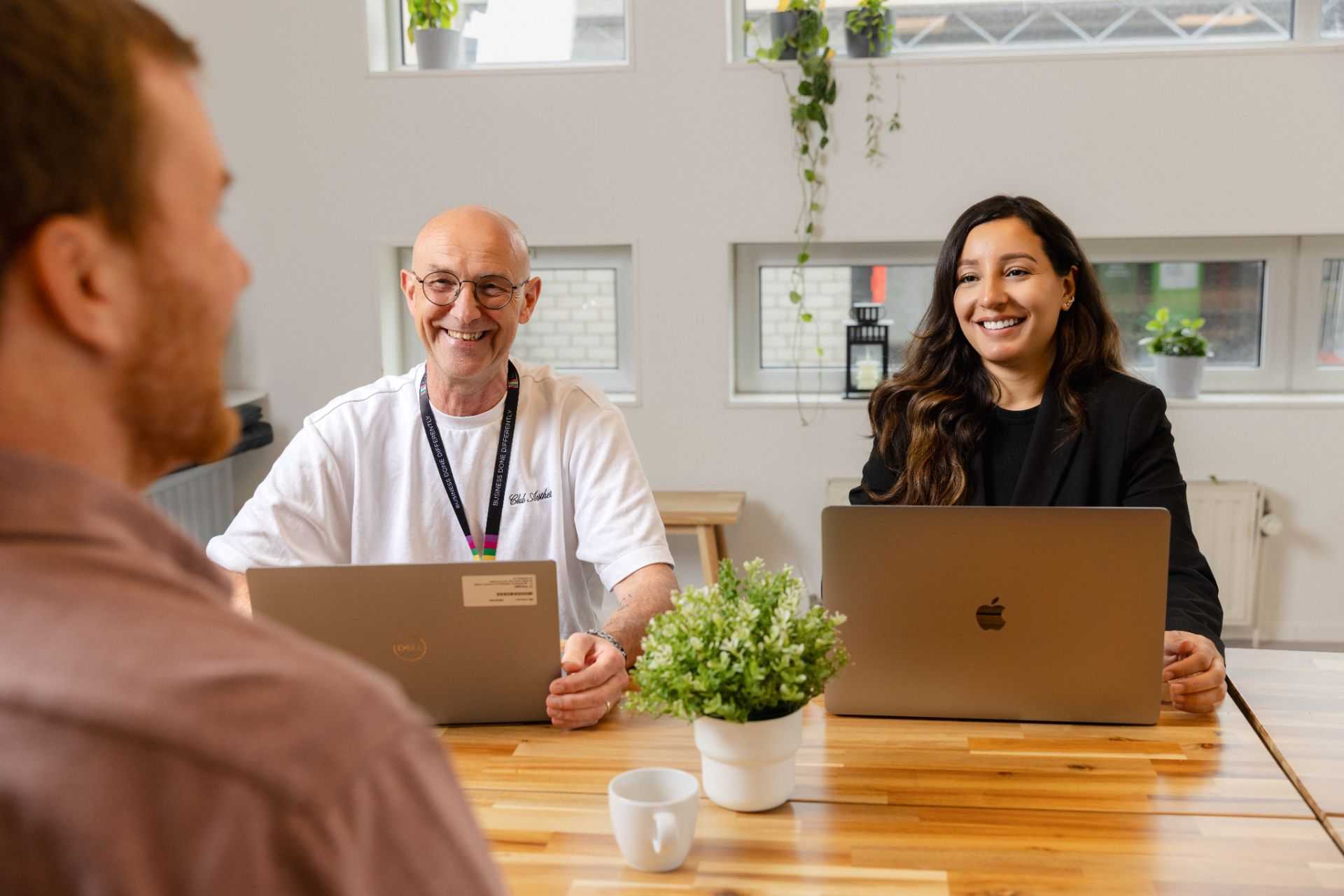 Two colleagues are working together on a computer and laughing.