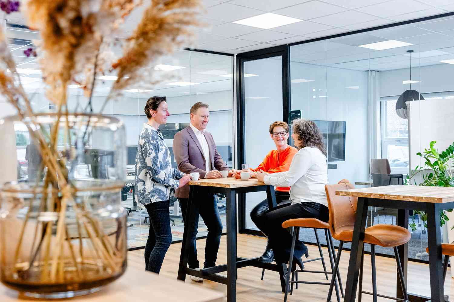 Groep mensen praat rond een tafel in een vergaderruimte.