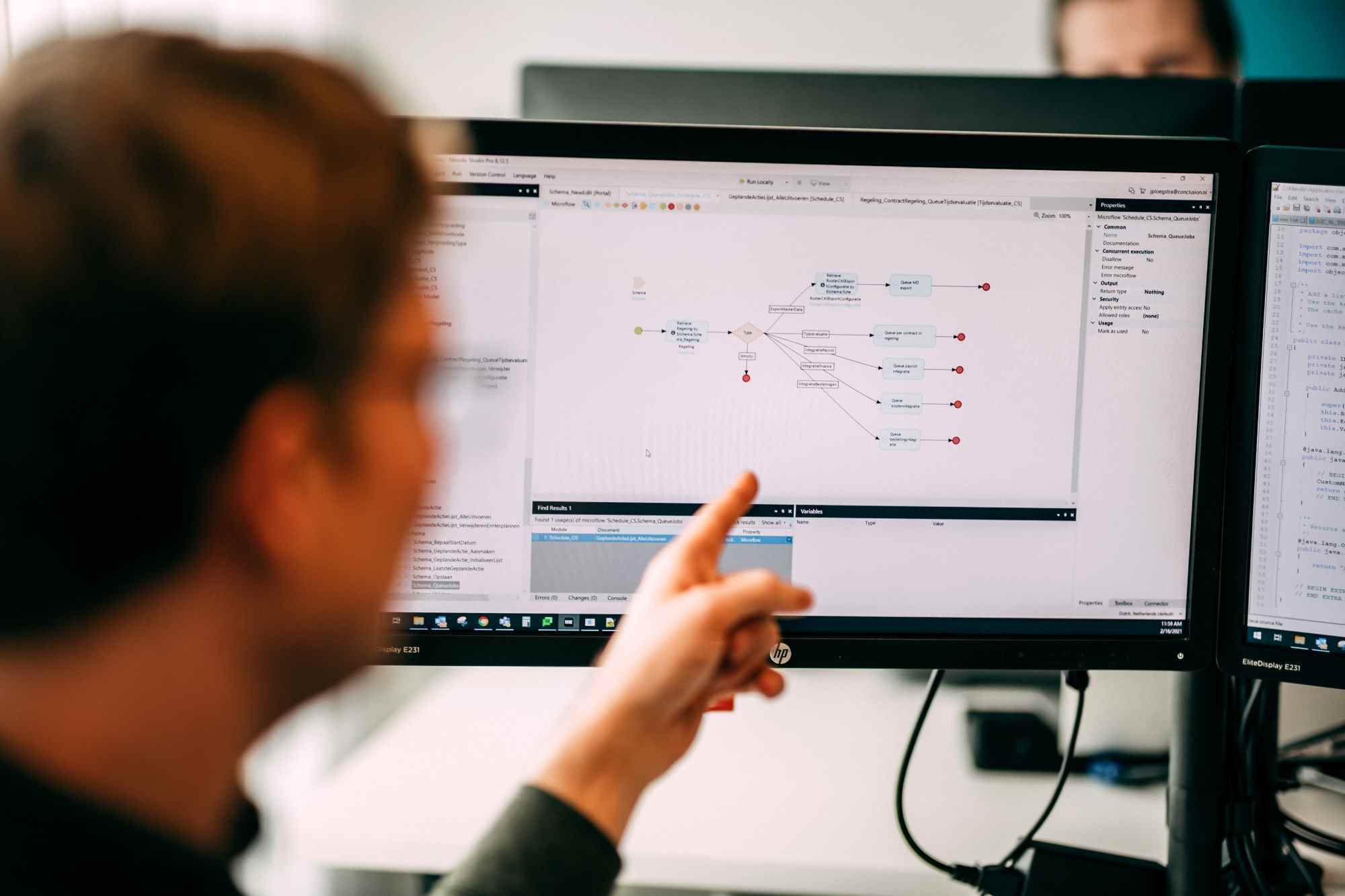 Man points to a screen with a visual representation of code and processes.