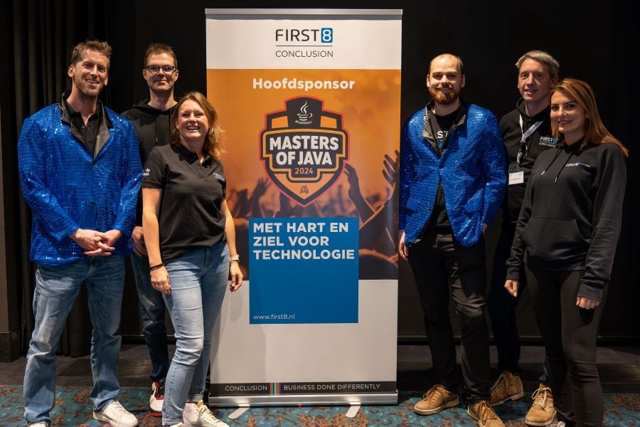 A group of people stands next to a banner for the Masters of Java 2024, with First8 as the main sponsor.