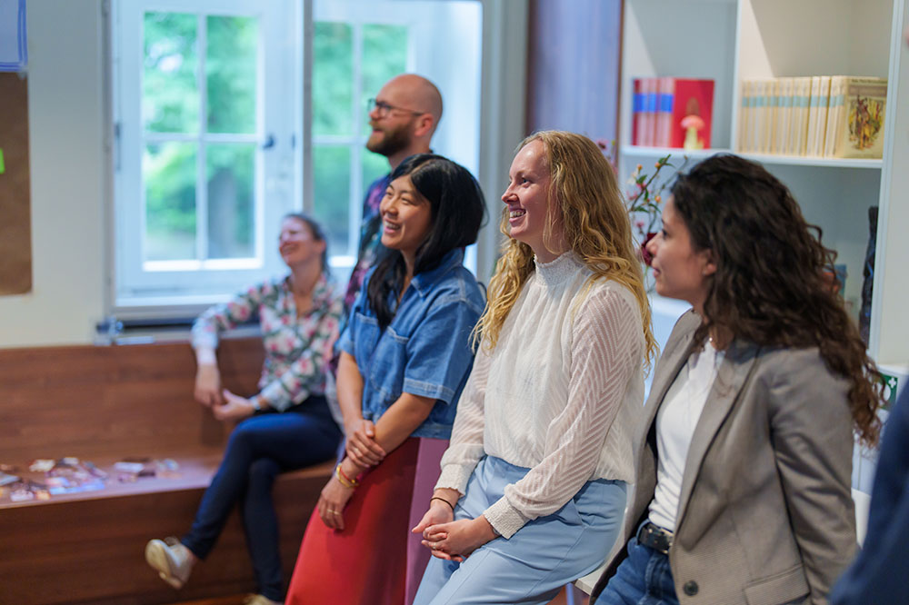 Five people laughing together in a room.