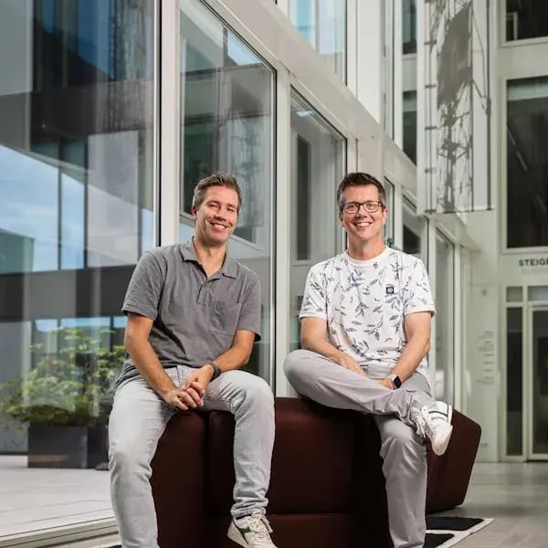 Paul en Emiel naast elkaar op een donkere rode stoel