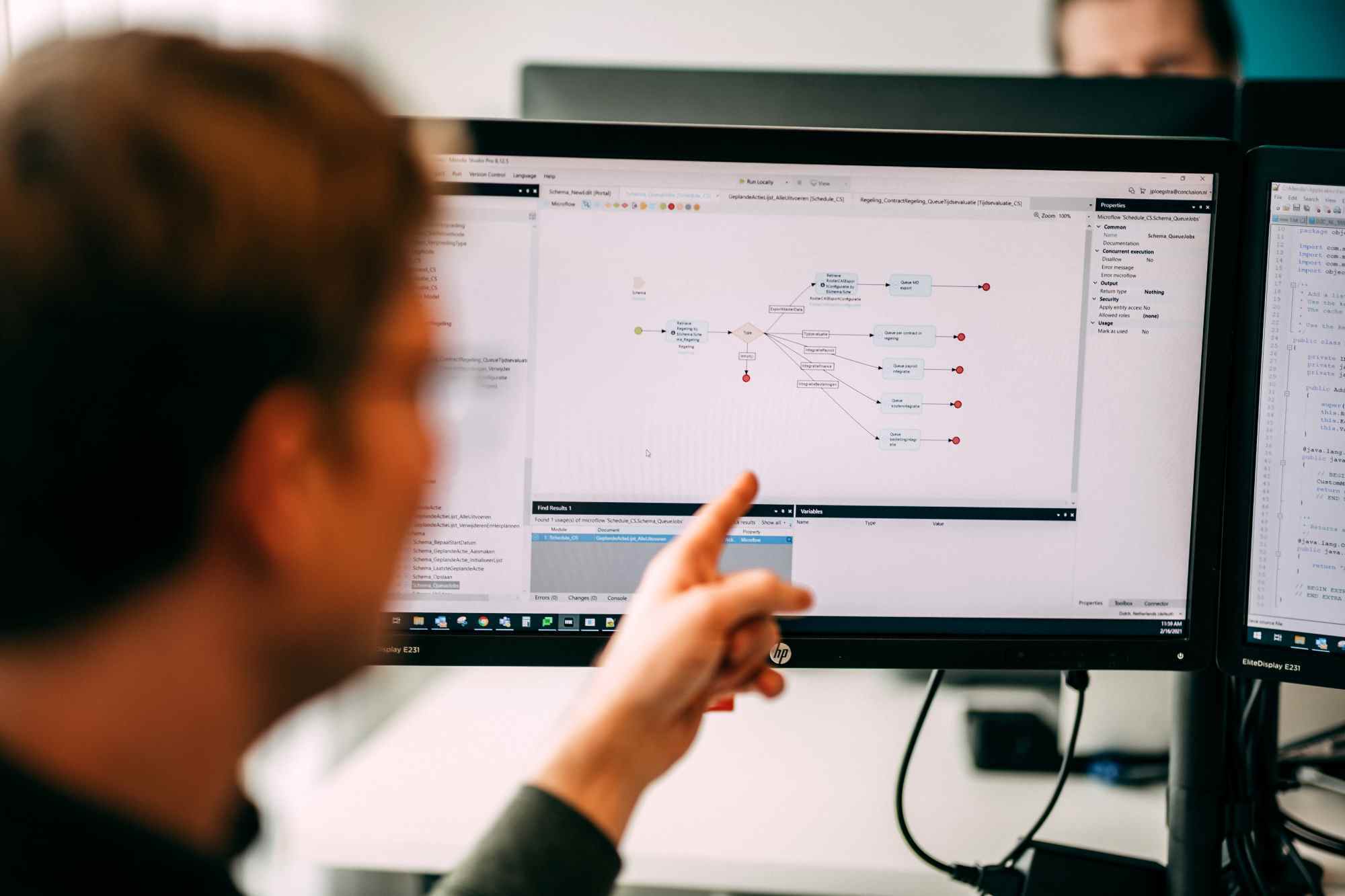 Man points to a screen with a visual representation of code and processes.
