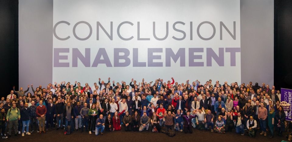 A group of people pose for a photo with the 'CONCLUSION ENABLEMENT' logo in the background.