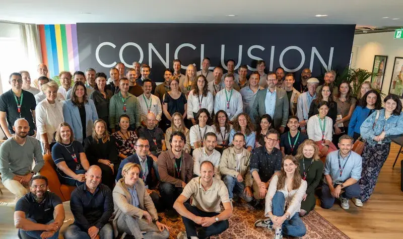 Groepsfoto voor de Conclusion muur